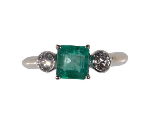 AN EMERALD AND DIAMOND THREE STONE RING the square-cut emerald, flanked to either side by a round-cut diamond on a hallmarked