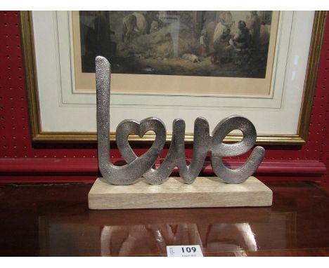 A cast metal Love message on light oak stand