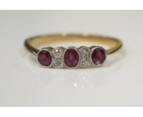 An 18ct Yellow Gold Seven Millegrain Set Stone Ruby and Diamond Ring, the central oval cut stone c. 3.8x2.9mm, size O.5, 2.3g