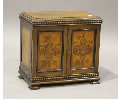 An Edwardian figured mahogany parquetry veneered table-top cabinet, fitted with slides and enclosed by two fielded panel door