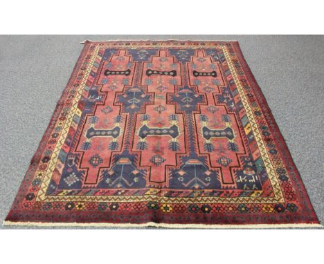 A Kurdish carpet, 20th century, the pink field with offset rows of shaped medallions, within a flowerhead border, 265cm x 193