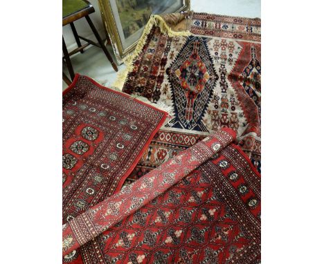 A Persian wool carpet with intricate rust, cobalt blue and brown woven decoration, 210cms wide and two similar smaller ground