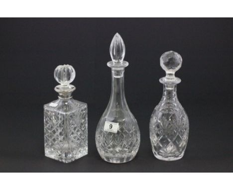 A cut glass decanter with a silver collar, along with two other glass decanters 