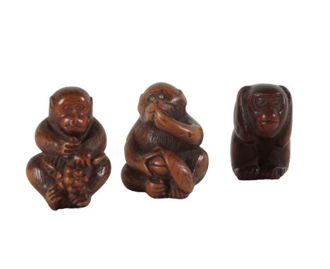 A GROUP OF THREE JAPANESE CARVED WOOD NETSUKE, ONE SIGNED BY YOSHINOBU Edo period, two examples of monkeys with fruit, the ot