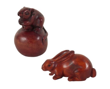 TWO JAPANESE CARVED WOOD NETSUKE one example, in the form of a field mouse atop a nut, 5.5cm high, the other modelled as a lo