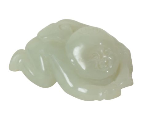 A CHINESE PALE CELADON JADE CARVING OF A BOY lying on his front, holding a vine to his back, 5.5cm long 