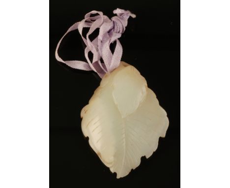 A CHINESE PALE CELADON JADE PENDANT Qing, carved on one side with a squirrel and vines on a leaf, 6cm long