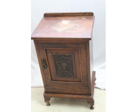 Edwardian oak bedside cabinet with decorative carved and panelled door with brass latch, one shelf inside, short cabriole leg