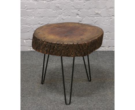 A rustic tree trunk slice top coffee table, raised on hair pin legs.