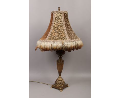 A table lamp with fur effect shade and feather fringe, raised on a glass and gilt metal base.