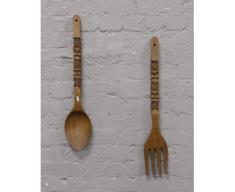 A large carved wooden novelty fork and spoon decorated with Aztec type figures.
