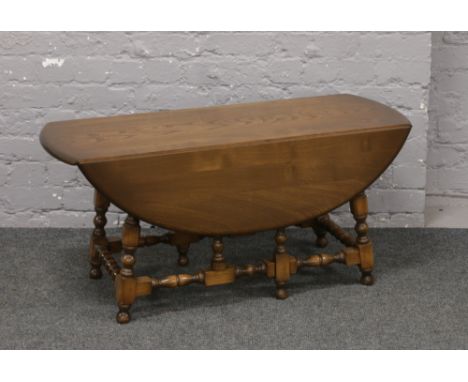 An Ercol Golden Dawn drop leaf coffee table raised on turned supports.