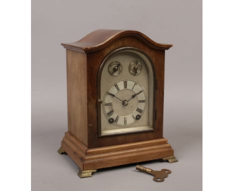 A walnut 8 day cased bracket clock with silvered dial having a twin train movement chiming on a coiled gong.