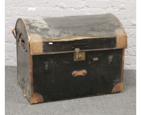 A black canvas dome top travel trunk with leather reinforced shoulders and internal tray.