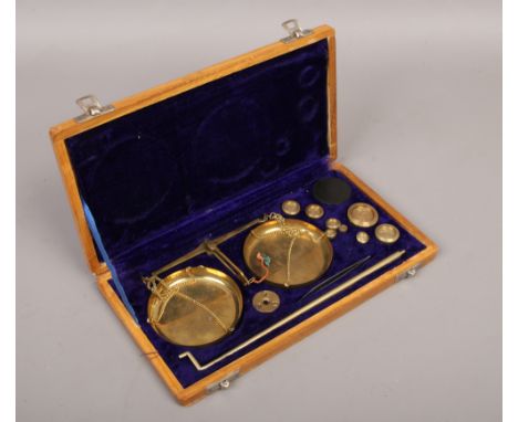 A cased set of brass balance scales with weights.