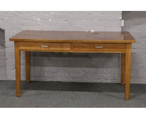 A mid 20th century light oak two drawer desk.