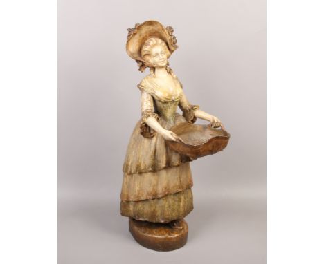 A large Goldscheider painted terracotta figure formed as a maiden wearing a bonnet and holding a basket, marked.