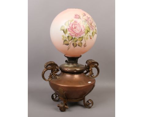 A large Victorian copper oil lamp with scrolling handles formed as mythical beasts and raised on wrought iron feet, along wit