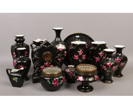 A collection of 20th century English black ground pottery decorated with roses to include posie bowls, mantle clock and wall 