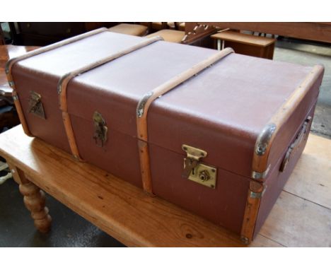 A large vintage banded travel trunk with metal fittings and leather handles