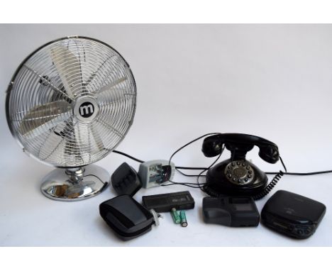 A vintage rotary dial telephone, along with an electric fan and various electrical accessories