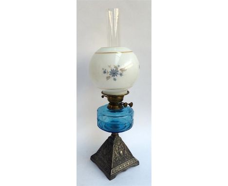 A 19th century oil lamp with brass fittings and blue glass reservoir, raised on a square pyramid white metal base, with glass