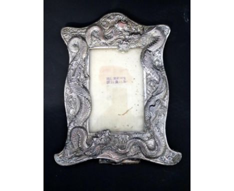 Early 20thC Oriental Silvered Metal Photo Frame, Of Shaped Form Depicting Two Embossed Dragons Chasing The Pearl. 10 x 8 Inch