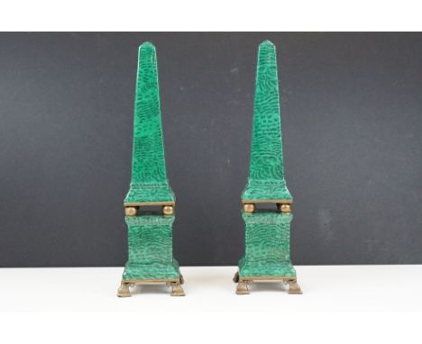 A pair of ceramic obelisks with faux malachite green finish upon four footed cast metal stands, height is approx 35cm.