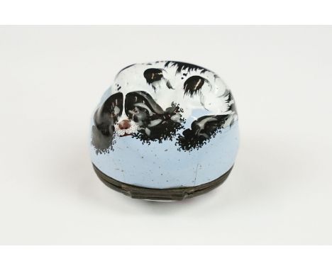 An antique Enamel Spaniel Patch Box, the black and white painted dog lying on a blue cushion, the lid painted with a stylised