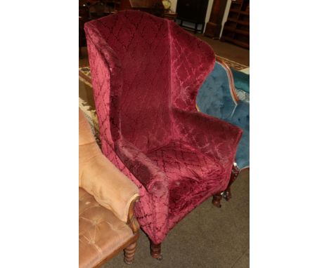 A 19th century ruby red upholstered wingback armchair 