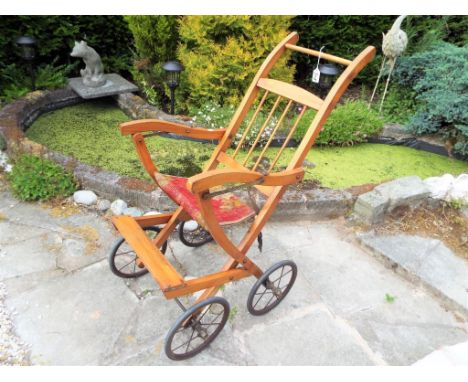 An Edwardian folding doll's pushchair, wood with carpet seat, spoked wheels, 89 cm (H)  This lot MUST be paid for and collect