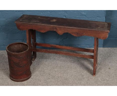 A carved wooden bench along with a leatherette bin.  