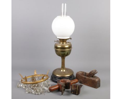 A brass oil lamp along with a small bag chandelier and vintage hand tools.  
