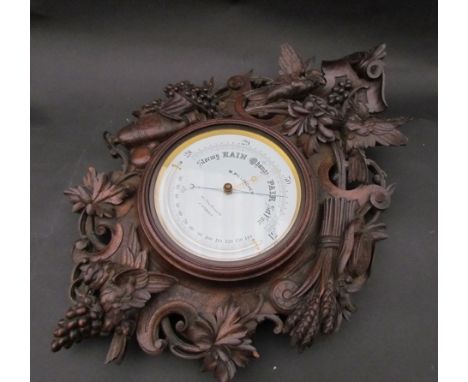 A large ornately carved oak cased aneroid barometer/thermometer, maker M. Pillischer, 88 New Bond St,  London