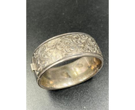 A silver hinged bangle with foliate decoration