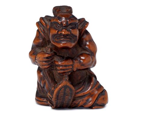 A Japanese wood netsuke of a temple guardian (Nio), 19th/20th c, carrying a large pair of straw sandals (waraji) with a strai