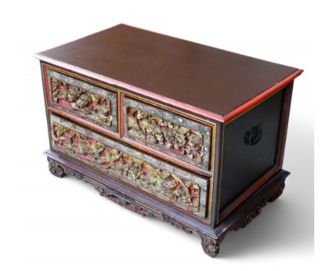 A Malaysian red painted chest, with two short over one long drawer, the drawer fronts carved, gilt painted and with borders o