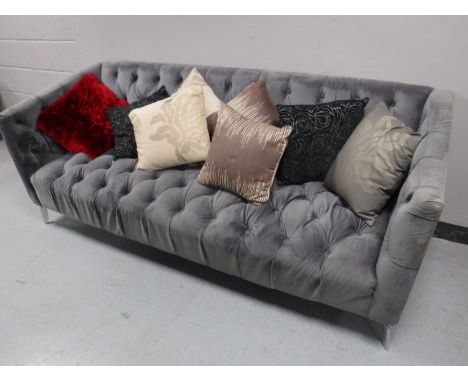 A contemporary three seater settee, upholstered in a button fabric, with eight miscellaneous scatter cushions