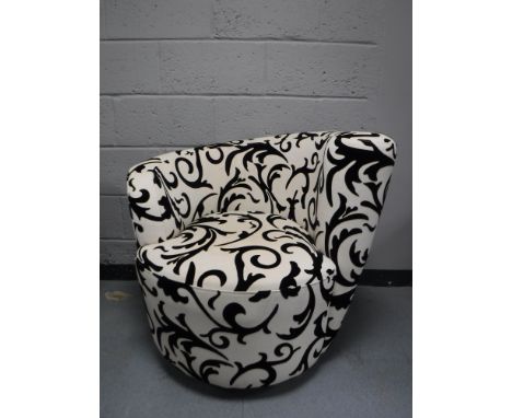 A contemporary swivel armchair, upholstered in a black and white fabric with a red cushion