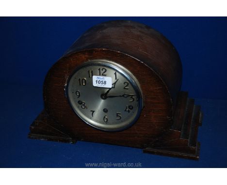 A Deco Oak cased mantle Clock, oval cased on stepped plinth base, circular alloy Arabic numeral face with eight day movement,