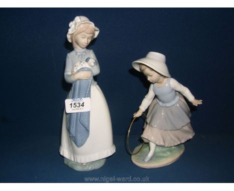 Two Nao figurines, one of a girl with hoop, the other girl with puppy