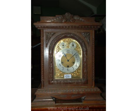 A carved Oak cased Bracket Clock by Kemp Bros, Bristol with three train movement and decorative gilt metal face, 18" tall, 14