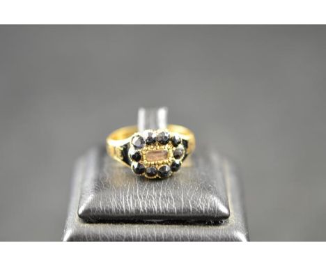 A Victorian 18ct gold mourning ring with black enamel decoration, set with central panel of woven hair bordered by ten jet st