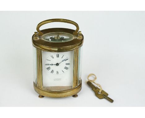 An antique brass cased carriage clock with bevelled glass panels and white dial, retailer marked for J. Vincent of Weymouth. 