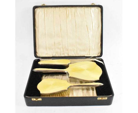 DANIEL MANUFACTURING COMPANY; a cased George V Art Deco yellow enamelled three piece silver dressing table set comprising two