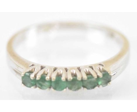 A 14ct white gold ring set with six small emeralds, size N, approx 2.4g.