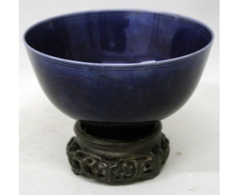 A CHINESE BLUE GLAZED PORCELAIN BOWL, together with a wood stand, the sides with underglaze decoration of formal flowerheads 