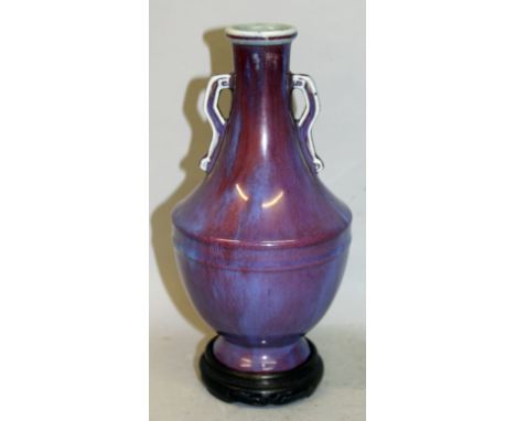 A CHINESE FLAMBE GLAZED PORCELAIN VASE, together with a fitted wood stand, the neck with moulded scroll end handles, the side