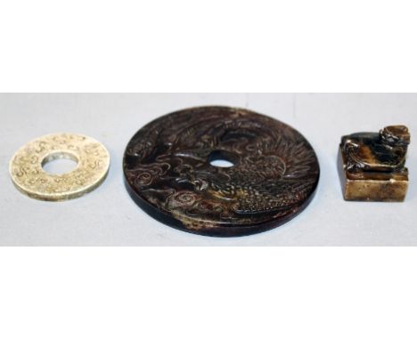 A CHINESE BROWN JADE-LIKE BI DISC, each side decorated in relief with a phoenix, 3.9in diameter; together with a smaller bi d