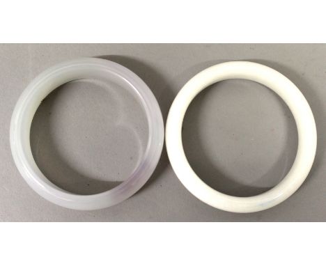 A FURTHER TWO CHINESE JADE-LIKE BANGLES, one of pale lilac hue, the other of mottled white, 2.8in & 2.9in diameter; the inner